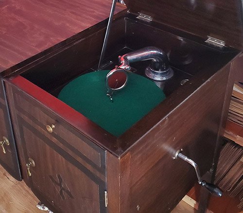 Gramophone ancien avec pavillon en laiton et coffret en bois sculpté, posé sur une table